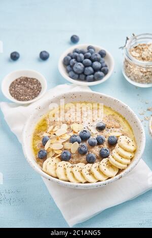 Haferflocken mit Heidelbeeren, Banane auf blauem Hintergrund Stockfoto