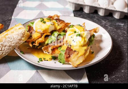 Sandwich mit Eiern Benedict, Speck und Salat auf schwarzem Stein Hintergrund. Stockfoto