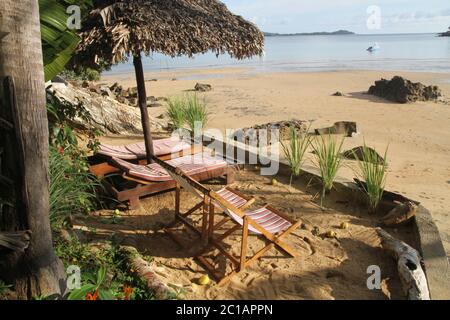 Liegestühle, Stühle, Zitronengras unter Palmleaved Stroh Lapa auf Breach, Ampangorinana Village, Nosy Komba Island, Magadascar. Stockfoto