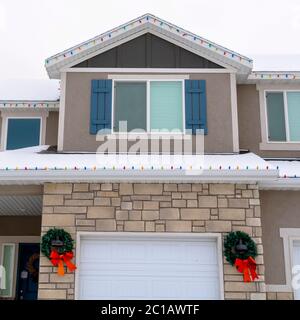Square Home Fassade mit festlichen Weihnachtskränzen und bunten String Lichter im Winter Stockfoto