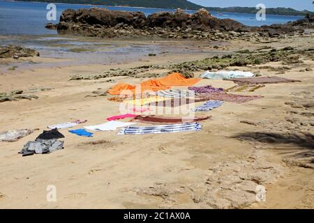 Kleidung, Decken und Wäschetrocknung auf dem Strandboden, Ampangorinana Village, Nosy Komba Island, Madagaskar. Stockfoto