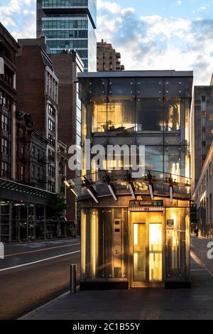 Der Aufzug der U-Bahn-Station in New York City leuchtet mit dem Licht des Sonnenuntergangs, der durch Glasscheiben auf der 23rd Street in Manhattan NYC scheint Stockfoto