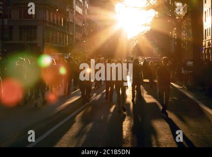 Menschenmenge, die die Straße hinunter in das helle Licht des Sonnenuntergangs in New York City NYC geht Stockfoto