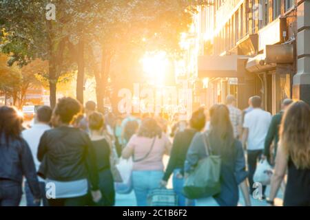 Menschenmenge anonymer Leute, die den Bürgersteig auf einer belebten Straße in Manhattan, New York City mit einem hellen Sonnenlicht Hintergrund, hinuntergehen Stockfoto