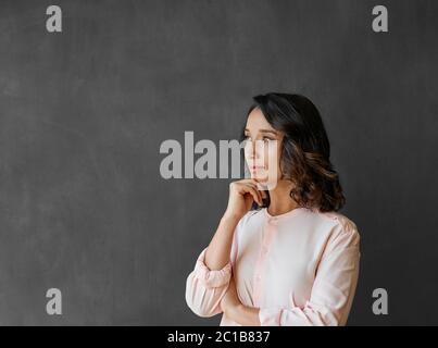 Junge asiatische Geschäftsfrau steht an einer Tafel tief in Gedanken Stockfoto