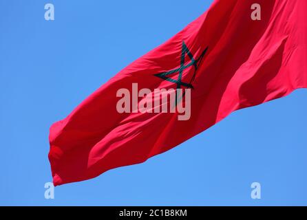 Marokko. Die marokkanische Nationalflagge winkt im Wind gegen einen klaren blauen Himmel. Stockfoto