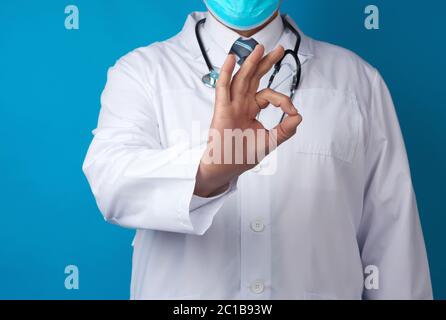 Mann Arzt in weißem Mantel zeigt ok Geste mit der Hand, Konzept der Hoffnung, dass alles in Ordnung sein, blauer Hintergrund Stockfoto