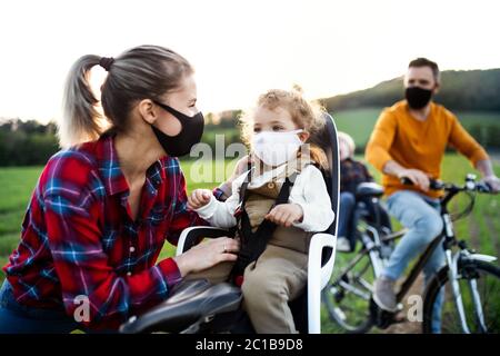 Familie mit zwei kleinen Kindern auf Radtour, mit Gesichtsmasken. Stockfoto