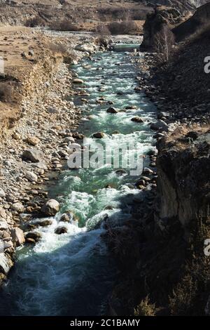 Stürmischer Gebirgsfluss mit Steinspritzern und Schaum mit klarem Trinkwasser von smaragdgrüner Farbe. Das Konzept der natürlichen Quellen o Stockfoto