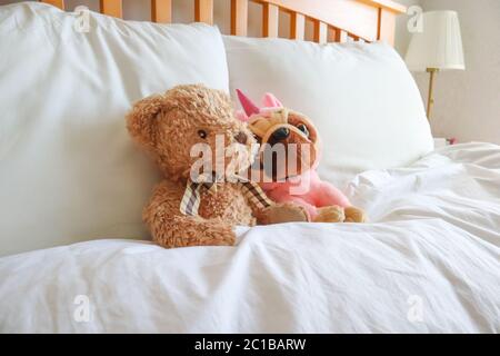 Zwei Teddys im Bett, mit weißer Bettwäsche, in einem hellen, luftigen Schlafzimmer Stockfoto