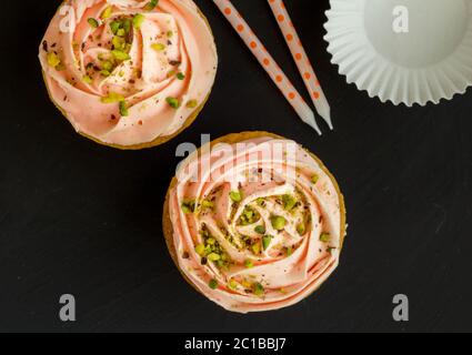 Ansicht von oben mit zwei verzierte Cupcakes, Kerzen und Papier auf schwarzem Schiefer Hintergrund Stockfoto