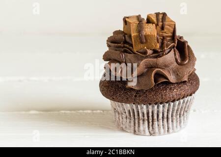 Schokolade Kuchen dekoriert mit Mini fudge Quadrate auf weißen rustikalen Tisch Nahaufnahme Stockfoto