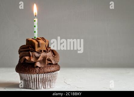 Eine Chocolate Caramel Cupcake mit auf dunkelgrauem Hintergrund Kerze angezündet - Platz für Text Stockfoto