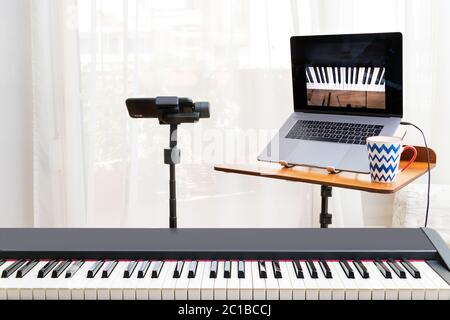 Online Piano Lessosn Setup mit einem Laptop, einem Klavier-Tastatur und einem Smartphone auf einem Gimbal als Kamera. Stockfoto