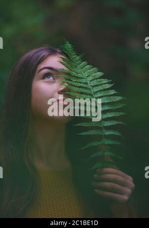 Nahaufnahme Porträt einer jungen Frau auf einem Spaziergang im Freien im Wald in der Natur, halten Farn. Stockfoto