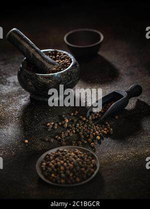 Rohe organische schwarze Pfefferkörner Konzept auf dunklem Hintergrund Stockfoto