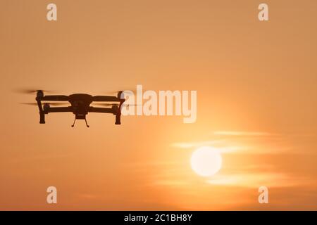 Drone quad Copters mit hochauflösenden Digitalkamera fliegende Antenne über spektakulären Sonnenuntergang orange sky Stockfoto