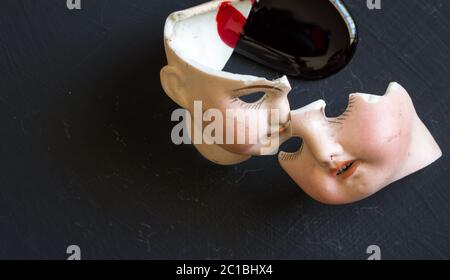 Zerbrochene Puppengesichter und Blut isoliert auf grunge schwarzem Hintergrund mit Blutspritzer. Konzeptionelles Image Stockfoto