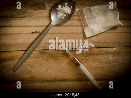 Drogen, Pulver, Spritze und Löffel auf rustikalem Holzboden Hintergrund. Drogenabhängigkeit Konzept backgroun Stockfoto
