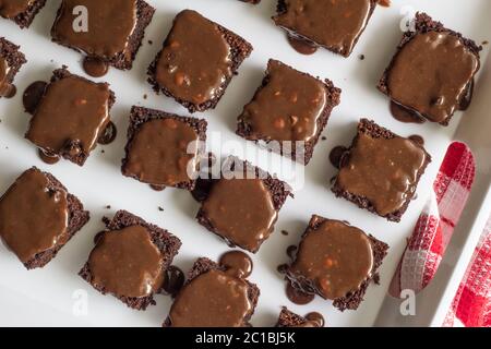 Schokolade Brownies mit Schokolade Nuss Ganache bedeckt - Close up Draufsicht der Brownie Quadrate in whit Stockfoto