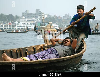 Sadarghat in Dhaka, Bangladesch. Ein Mann rudert sein kleines Boot über den Fluss bei Sadarghat in Dhaka mit einem sehr entspannten Passagier Stockfoto