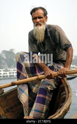 Sadarghat in Dhaka, Bangladesch. Ein Mann mit langem Bart rudert sein kleines Boot über den Fluss bei Sadarghat in Dhaka. Stockfoto