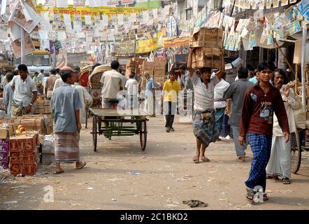 Eine belebte Straße im Stadtteil Sadarghat in Dhaka, Bangladesch. Eine belebte Menschenmenge auf einer Straße mit kleinen Geschäften, Bannern und Rikschas. Das lokale Leben, Dhaka. Stockfoto