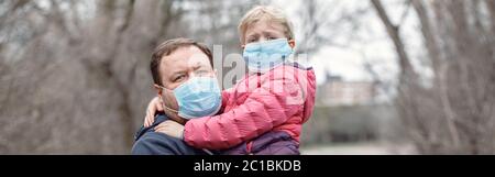 Vater mit Kind Mädchen tragen sanitäre Gesichtsmasken im Freien. Familie Vater und Tochter schützen sich vor gefährlicher Ausbreitung von Coronavirus covid-19. Stockfoto