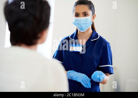 Krankenschwester, die mit dem Patienten spricht und die PSA trägt Stockfoto