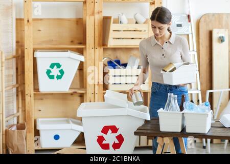 Junge Frau, die den Müll in den großen Papierkorb wirft, recycelt Abfall im Lager Stockfoto
