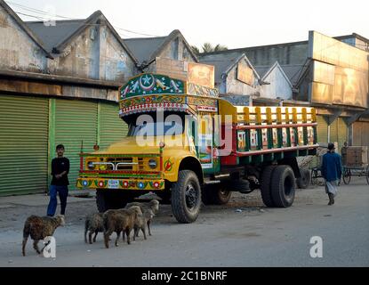 Ein farbenfroher LKW parkte auf der Straße in Khulna, Bangladesch. Menschen und einige Schafe oder Ziegen laufen am LKW vorbei. Lokale Szene in Khulna. Stockfoto