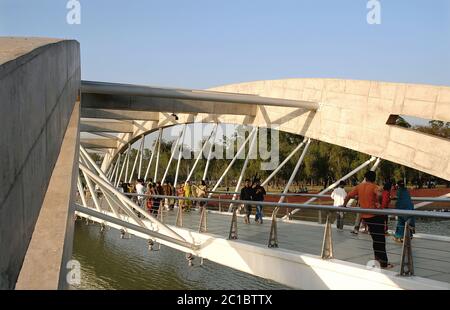 Dhaka in Bangladesch. Jatiya Sangsad Bhaban, das Nationalparlament von Bangladesch. Menschen, die eine Brücke auf dem Gelände des Gebäudes überqueren. Stockfoto