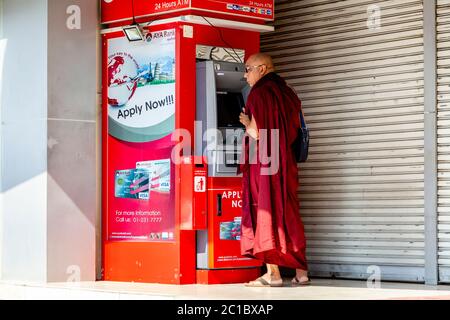 Ein buddhistischer Mönch zieht Bargeld von EINER Geldautomaten, Yangon, Myanmar. Stockfoto