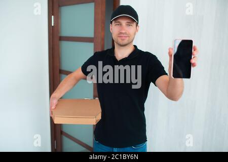 Konzept für die Lieferung von Lebensmitteln. Pizza Delivery Man Zeigt App Auf Smartphone Für Die Lieferung. Stockfoto