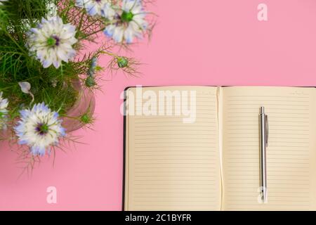 Bunte Frühlingsblumen mit leerem offenen Tagebuch auf pastellrosa Hintergrund, Draufsicht, flach liegend Stockfoto