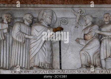 Der heilige Martin von Tours exorziert einen von einem Teufel verärgerten Mann (Dämon vexatum), während ein geflügelter Dämon mit Klauenfüßen über dem Kopf des Mannes schwebt. Szene aus „Storie di San Martino“, einer Serie romanischer Reliefs aus dem 13. Jahrhundert an der Fassade des Duomo di San Martino, Lucca, Toskana, Italien. Die Reliefs stammen möglicherweise von Guido di Bonagiunta Bigarelli (1220–ca. 1257), dem lombardischen Bildhauer Guido da Como, der die obere Fassade der Kathedrale baute. Stockfoto