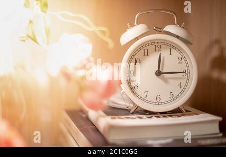 Klassische weiße Uhr auf dem Stapel von Büchern auf der hölzernen Kulisse für zeigen das Timing des Lebens und der Zeit ist wichtig Konzept. Stockfoto