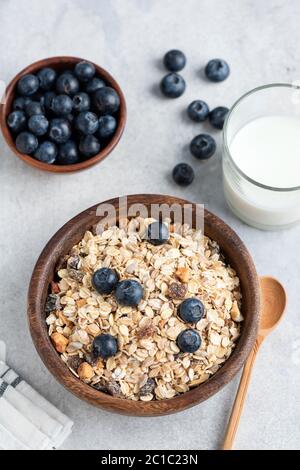 Hafermüsli mit Heidelbeeren in Schale und Glas Milch auf Betongrund. Gesundes Frühstücksangebot. Draufsicht Stockfoto