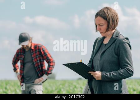 Hypothekendarlehen Officer Unterstützung Landwirt in finanzielle Zulage Antragsverfahren, Bankier und Landarbeiter in Mais Maisernte Feld. Stockfoto