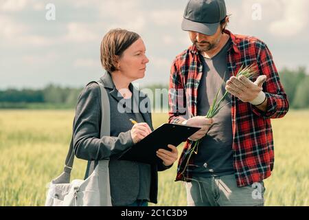 Hypothek Darlehen Officer Unterstützung Landwirt in finanziellen Zuschuss Antragsprozess, Bankier und Landarbeiter in Weizenfeld. Stockfoto