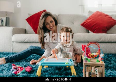 Junge hübsche Mutter spielt mit ihrer Tochter auf dem Boden im Wohnzimmer zu Hause Stockfoto