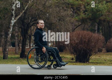 Junge behinderte Menschen im Rollstuhl Walking Park Stockfoto