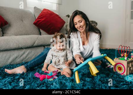 Junge hübsche Mutter spielt mit ihrer Tochter auf dem Boden im Wohnzimmer zu Hause Stockfoto