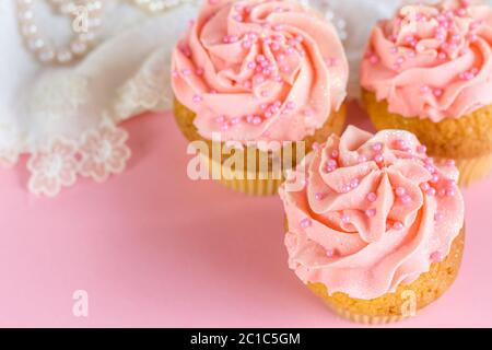 Rosa Glitzer und Perle verziert Tasse Kuchen aus nächster Nähe auf rosa Hintergrund mit defokussierten Spitze und Perle Stockfoto