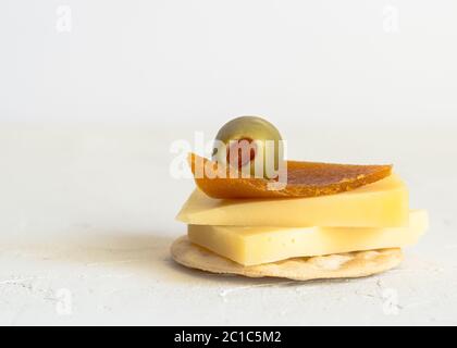 Käse auf Cracker mit piment Gefüllte grüne Oliven und getrocknete Pfirsich roll Dekoration isoliert auf weiss Stockfoto