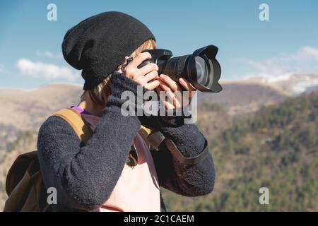 Nahaufnahme Porträt eines blonden Mädchen mit einer digitalen SLR-Kamera fotografieren in den Bergen. Stilvoller freiberuflicher Fotograf mit Stockfoto