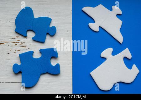 Zerlegte Puzzleteile auf weißer, rissiger Farbe. Blau-weiße Puzzleteile auf einem alten Holztisch. Das Konzept eines alten ungelösten Problems. Psychol Stockfoto