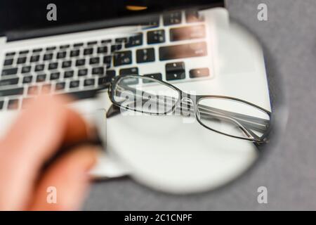 Schwarze umrandete umgekehrte Brille auf der Computertastatur mit einer sehr geringen Schärfentiefe. Stockfoto