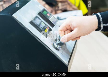 Eine Nahaufnahme einer Hand hält einen Drehschalter auf dem Bedienfeld der Geräte mit Instrumenten. Stockfoto