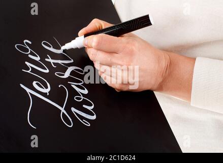 Frau, die auf einem kleinen schwarzen Brett schreibt, ohne dass die Schrift verschwendet wird, schließt sich an Stockfoto